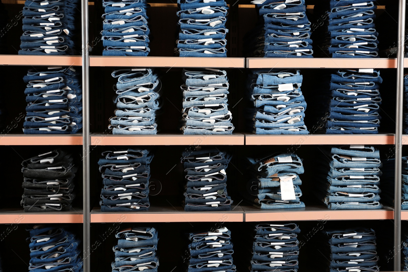 Photo of Collection of stylish jeans on shelves in shop