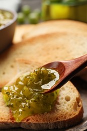 Photo of Spreading delicious gooseberry jam on toast closeup