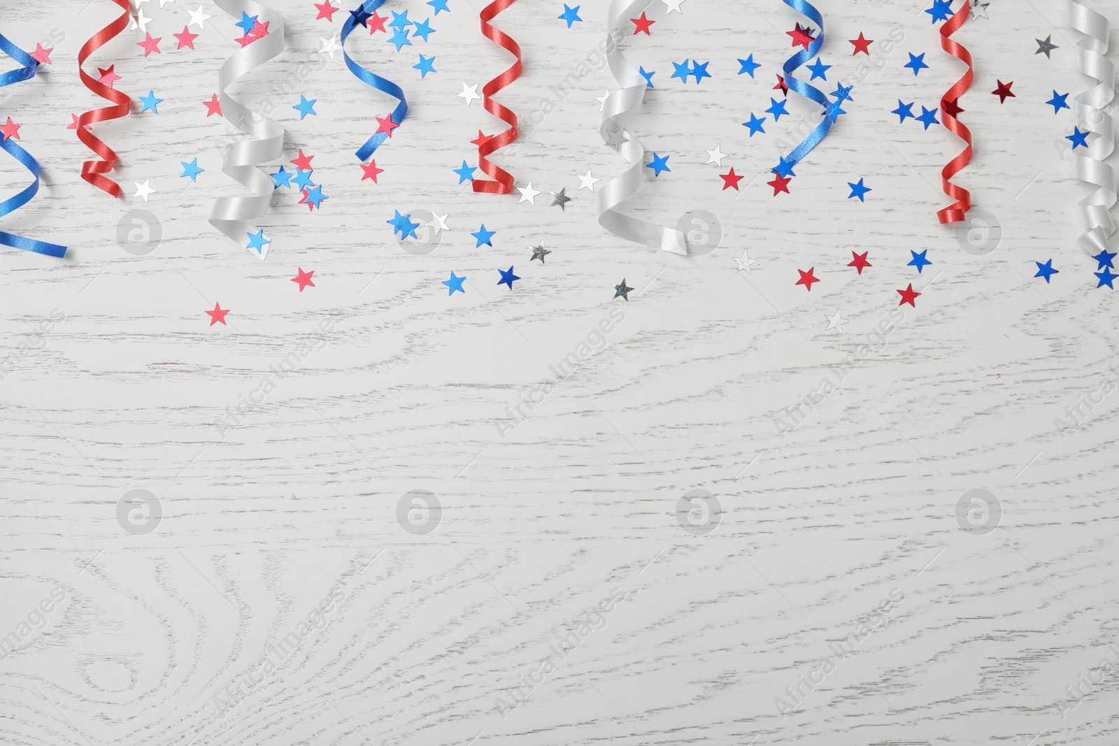 Photo of Flat lay composition with colorful party streamers on wooden table, space for text. USA Independence Day