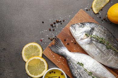 Fresh dorado fish and spices on black table, flat lay