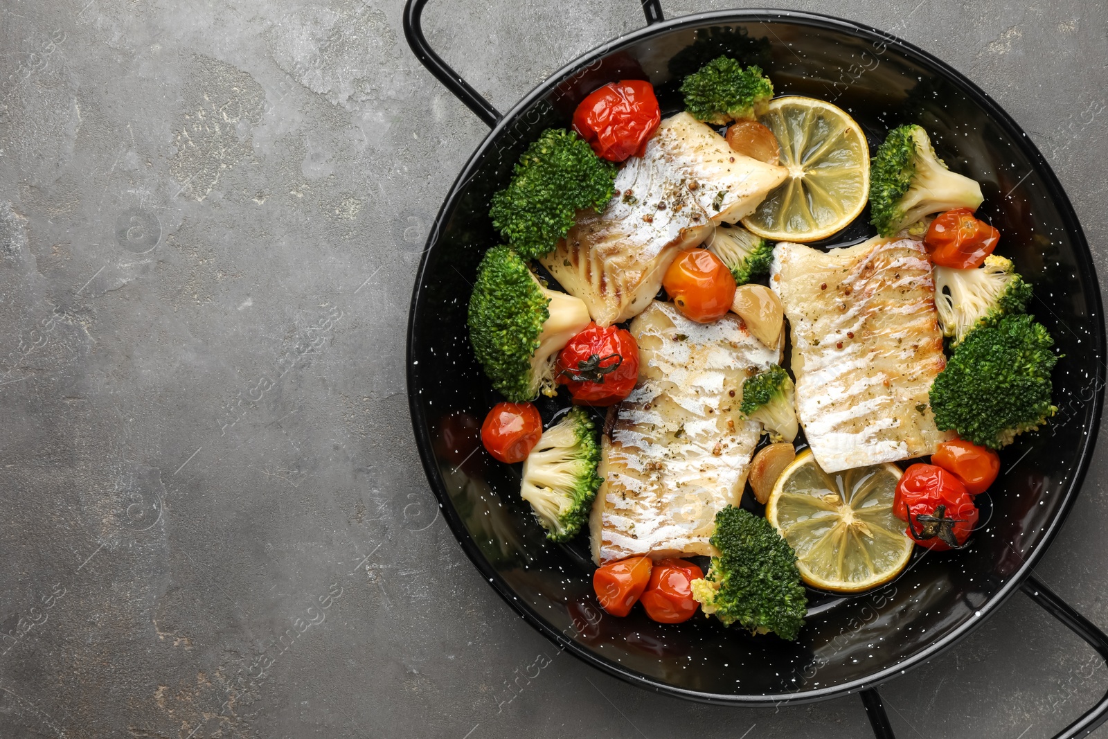 Photo of Tasty cod cooked with vegetables in frying pan on grey table, top view. Space for text