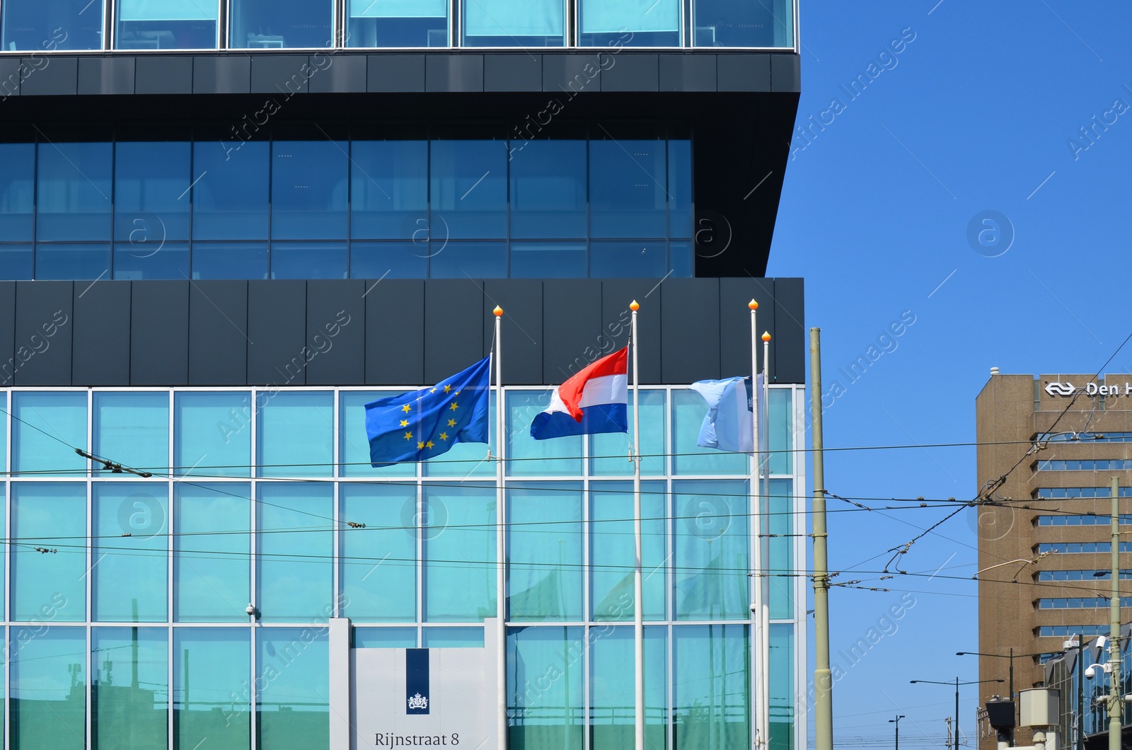 Photo of Hague, Netherlands - May 2, 2022: European Union and Netherlands flags fluttering near modern building in city