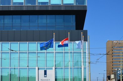 Hague, Netherlands - May 2, 2022: European Union and Netherlands flags fluttering near modern building in city