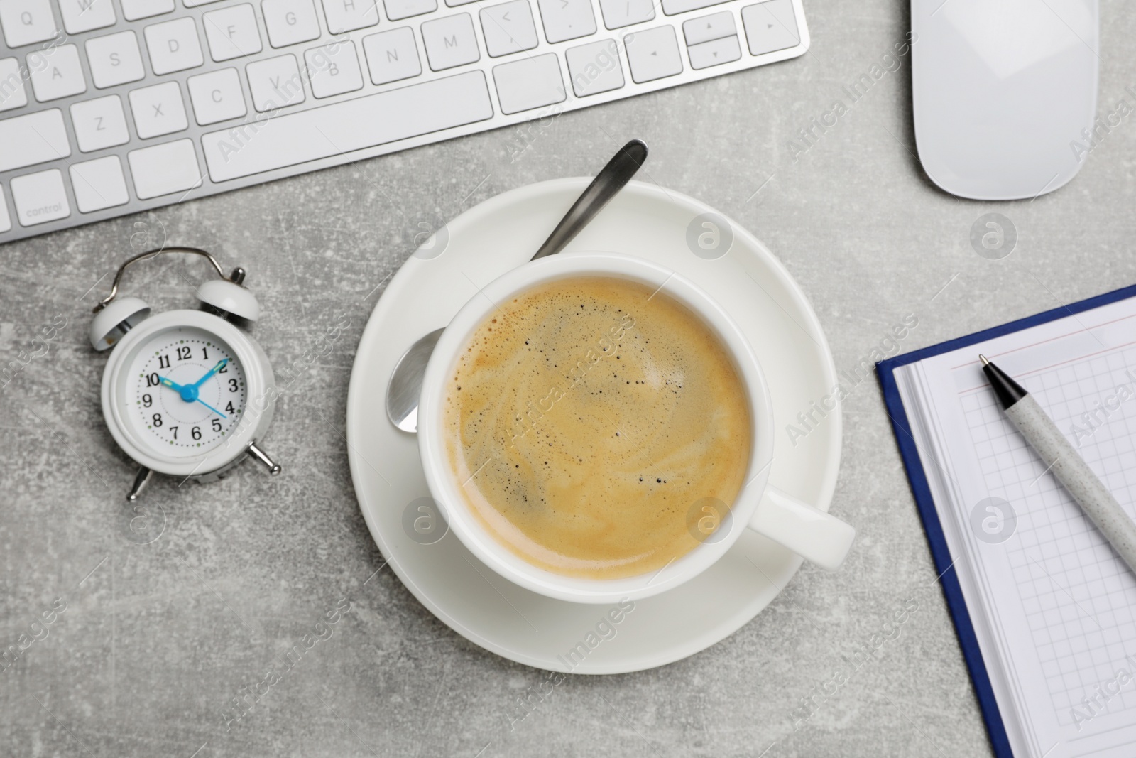 Photo of Cup of drink, alarm clock and stationery on light grey table, flat lay. Coffee Break