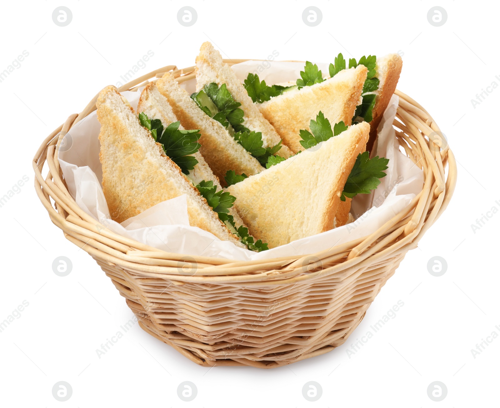 Photo of Tasty sandwiches with cucumber and parsley in wicker basket on white background