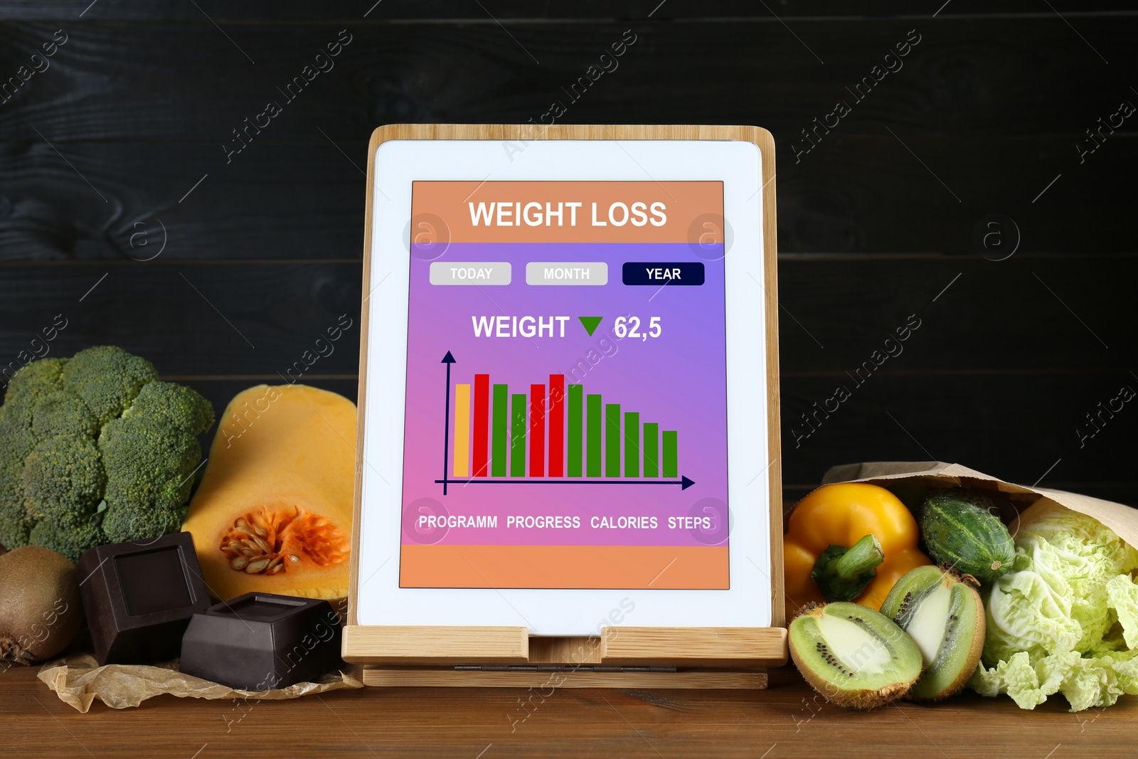 Photo of Tablet with weight loss calculator application and food products on wooden table