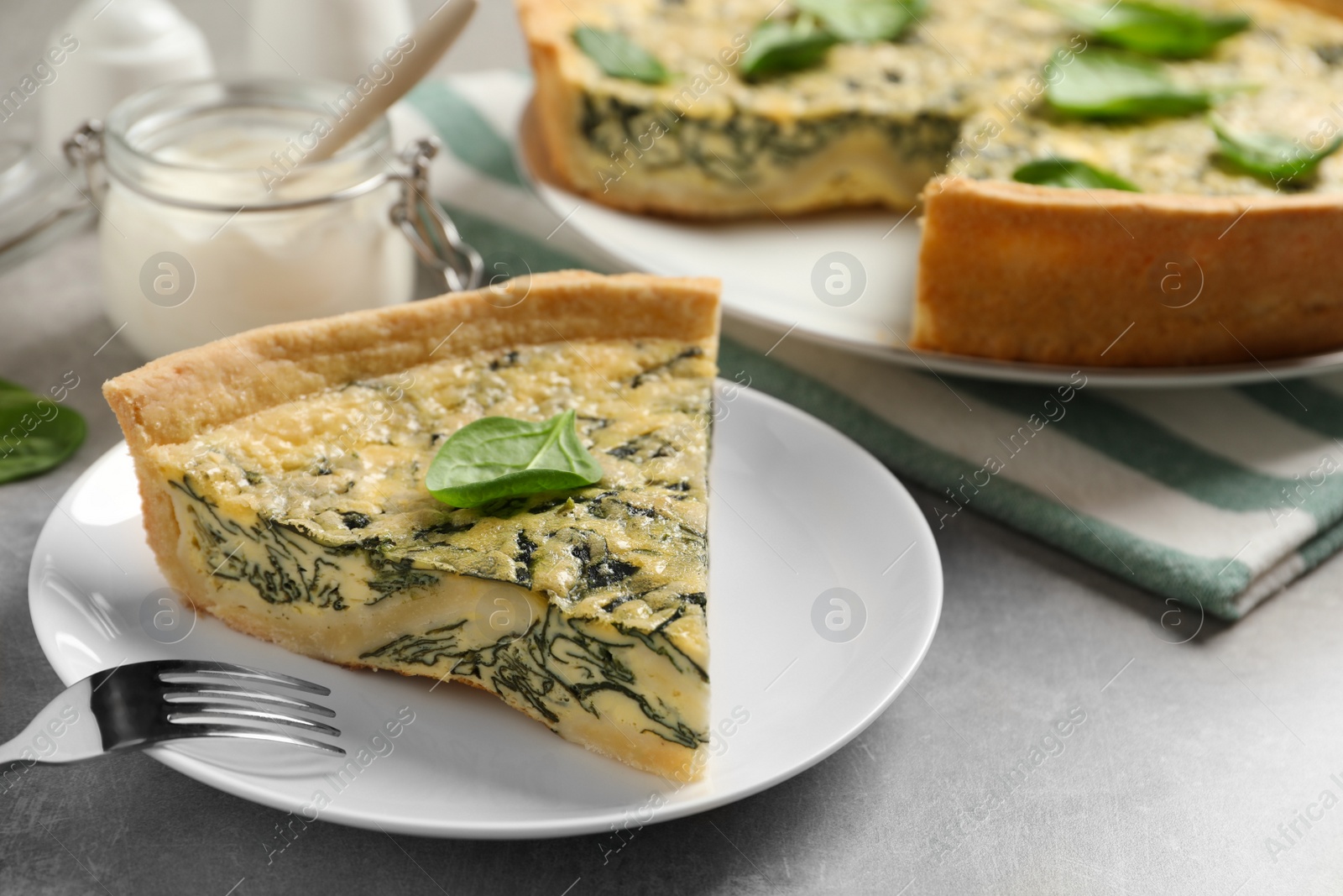 Photo of Piece of delicious homemade spinach pie served on grey table, closeup. Space for text