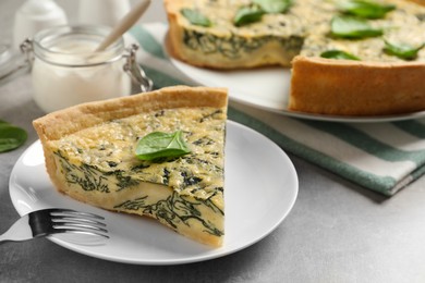 Piece of delicious homemade spinach pie served on grey table, closeup. Space for text