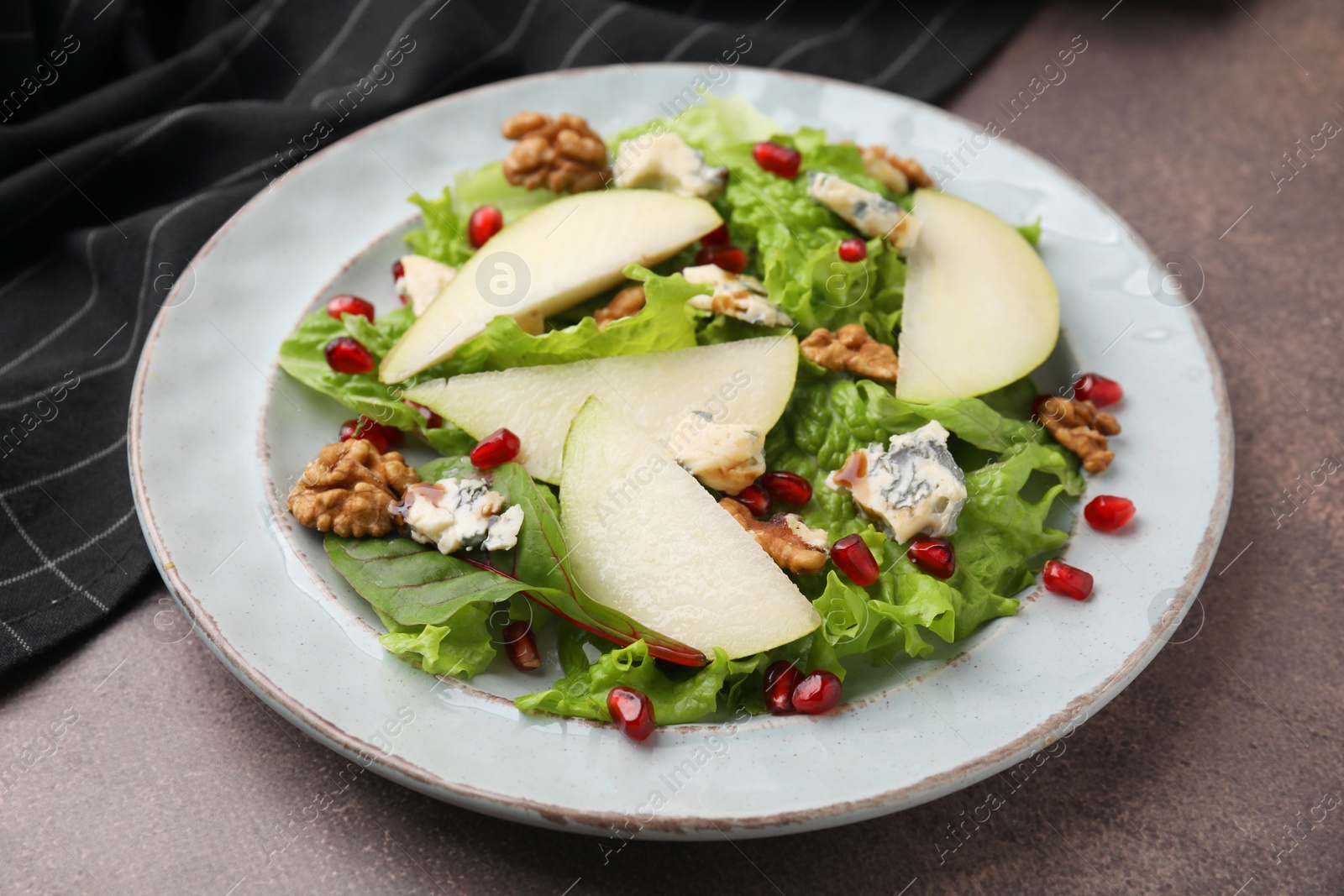 Photo of Delicious pear salad on dark textured table, closeup