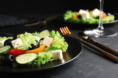 Photo of Tasty fresh Greek salad served on dark table
