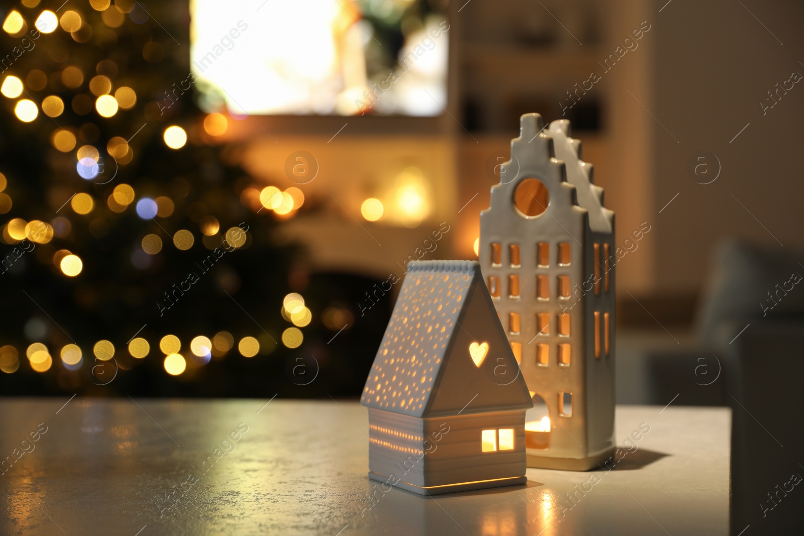Photo of Beautiful house shaped candle holders on table indoors, space for text. Bokeh effect