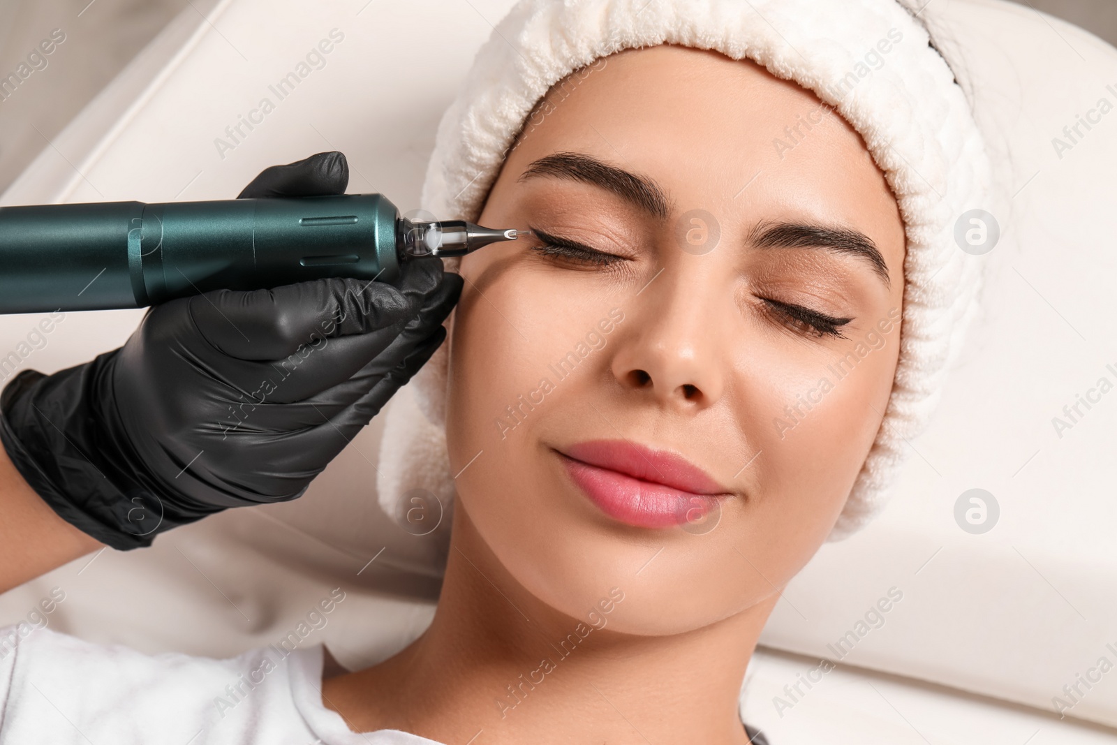 Photo of Young woman undergoing procedure of permanent eyeliner makeup, closeup