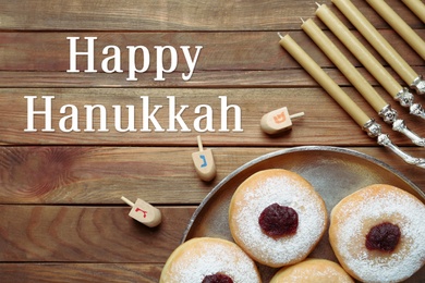 Happy Hanukkah. Flat lay composition with menorah, yellow candles, dreidels and sufganiyot on wooden table