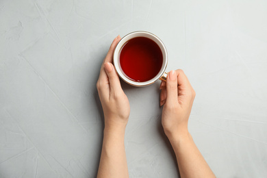 Woman with cup of tea at light table, top view