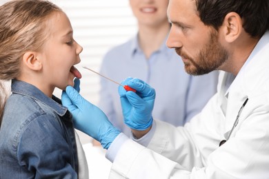 Photo of Doctor taking throat swab sample from girl`s oral cavity indoors