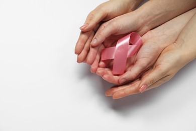 Photo of Breast cancer awareness. Women holding pink ribbon on white background, top view. Space for text