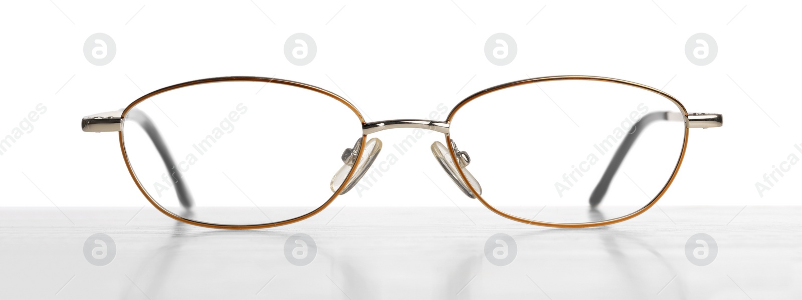 Photo of Stylish glasses with metal frame on table against white background
