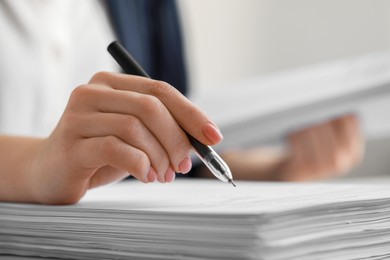 Woman signing documents at table in office, closeup. Space for text