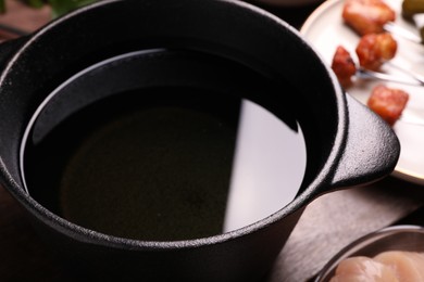 Fondue pot with oil on wooden table, closeup