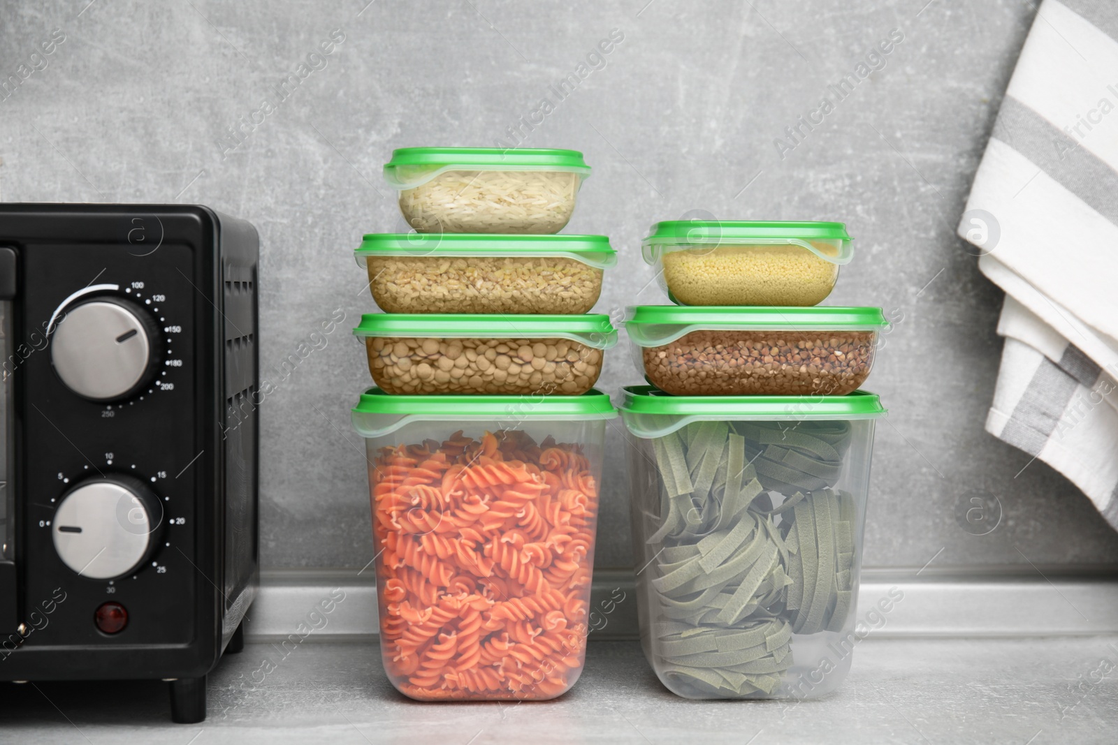 Photo of Plastic containers filled with food products on grey table in kitchen