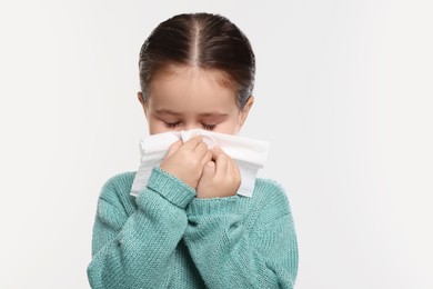 Girl blowing nose in tissue on white background. Cold symptoms