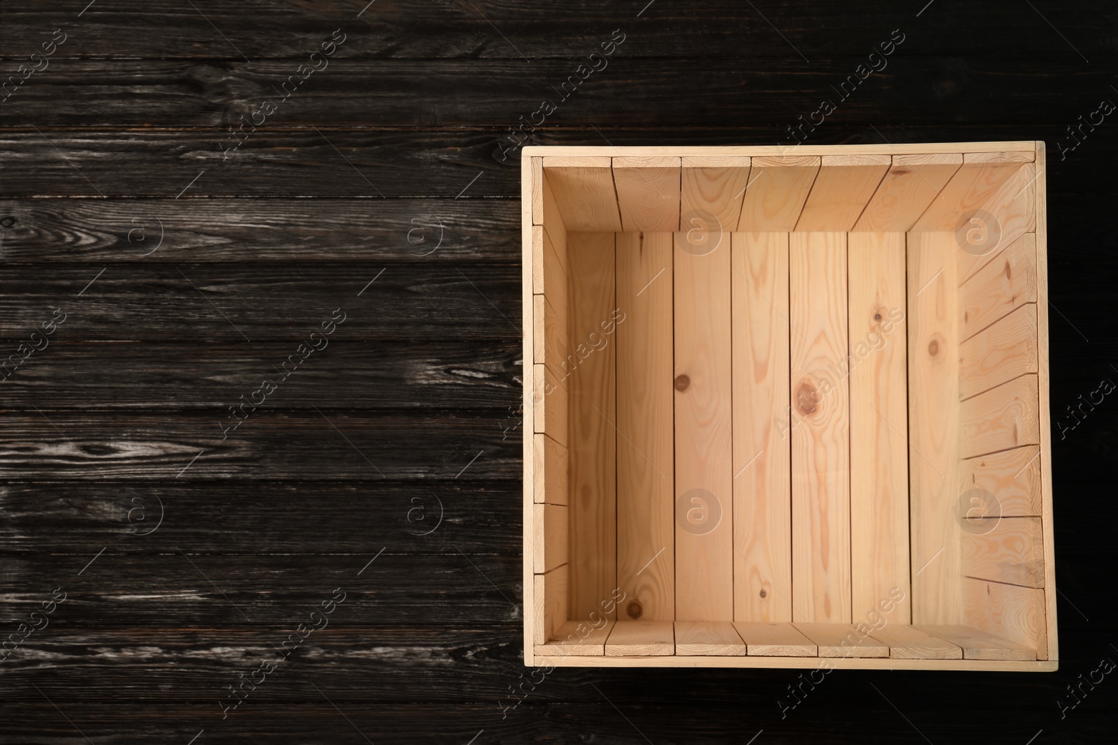 Photo of Open empty wooden crate on dark background, top view with space for text