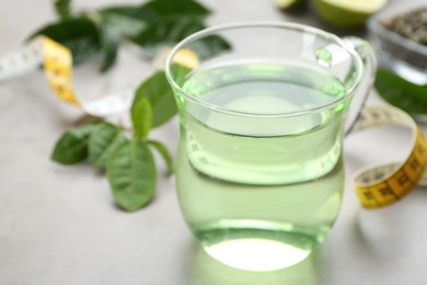 Photo of Herbal diet tea and measuring tape on light table, closeup