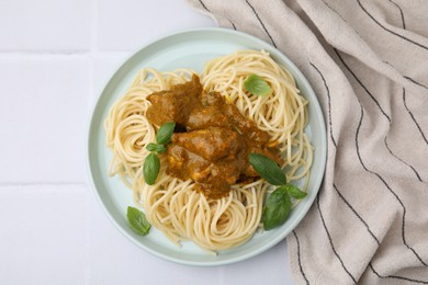 Photo of Delicious pasta and chicken with curry sauce on white tiled table, top view