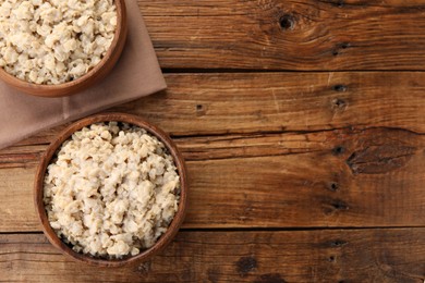 Photo of Tasty boiled oatmeal on wooden table, flat lay. Space for text