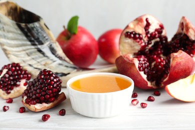 Photo of Honey, pomegranate, apples and shofar on white wooden table. Rosh Hashana holiday