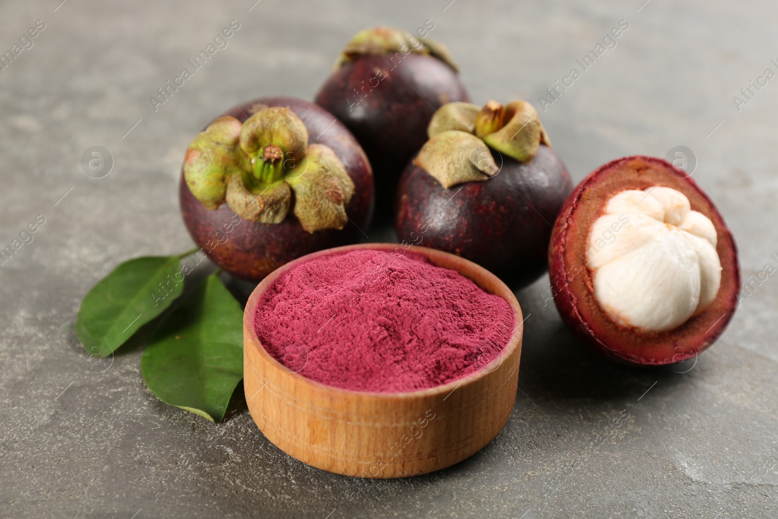 Photo of Purple mangosteen powder and fruits on grey table