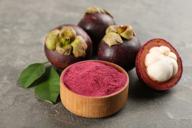 Purple mangosteen powder and fruits on grey table