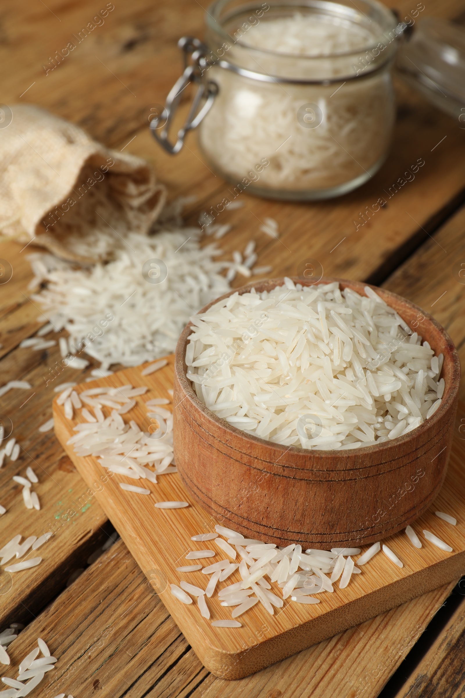 Photo of Raw basmati rice in bowl on wooden table, closeup