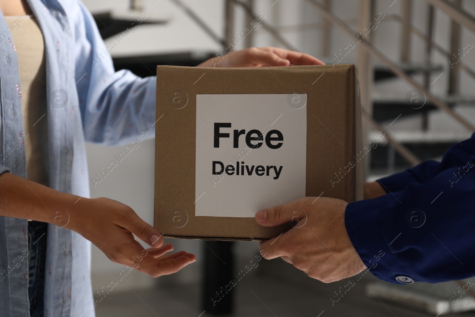 Photo of Woman receiving parcel with sticker Free Delivery from courier indoors, closeup