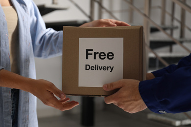 Photo of Woman receiving parcel with sticker Free Delivery from courier indoors, closeup