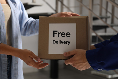 Woman receiving parcel with sticker Free Delivery from courier indoors, closeup