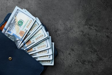 Photo of Dollar banknotes in wallet on grey table, top view with space for text. Money exchange