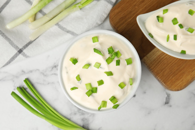 Photo of Fresh sour cream with onion on white marble table, flat lay