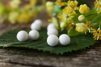 Photo of Homeopathic remedy and linden flowers on wooden table, closeup