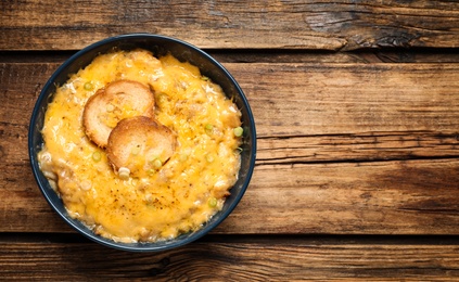 Photo of Tasty homemade French onion soup on wooden table, top view. Space for text