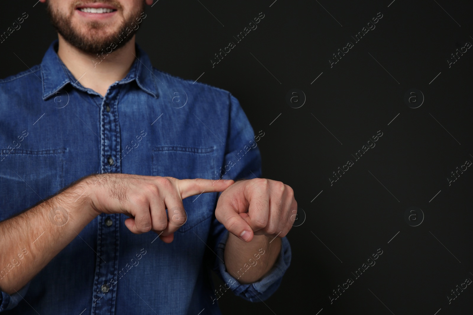 Photo of Man showing word TIME in sign language on black background, space for text