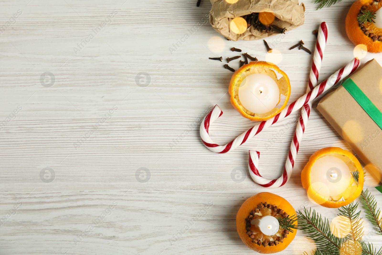 Photo of Flat lay composition with burning candles in tangerine peels as holders on white wooden table, space for text