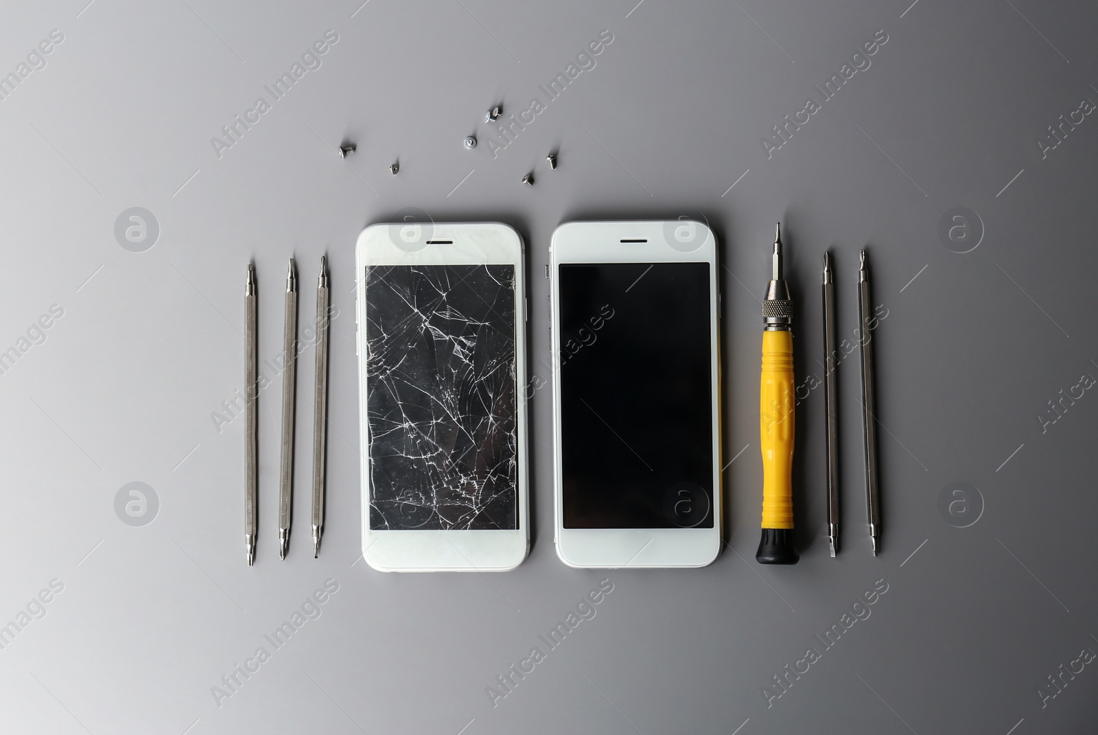 Photo of Flat lay composition with mobile phones and tools on grey background, space for text. Repairing service