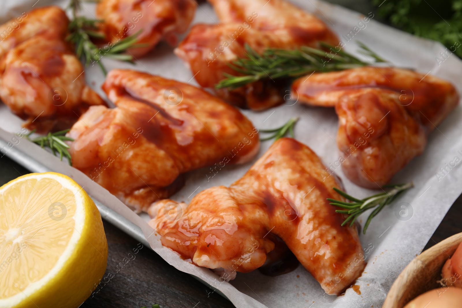 Photo of Raw marinated chicken wings, rosemary and lemon on table, closeup