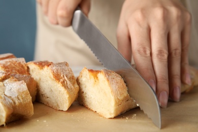 Photo of Woman cutting bread on parchment paper, closeup