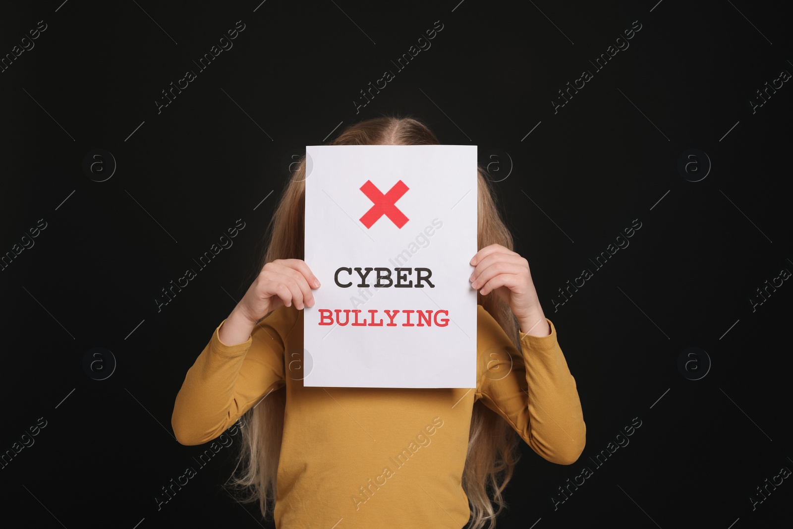 Photo of Girl holding sign with phrase Cyber Bullying on black background