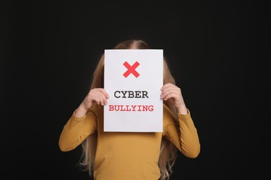 Photo of Girl holding sign with phrase Cyber Bullying on black background