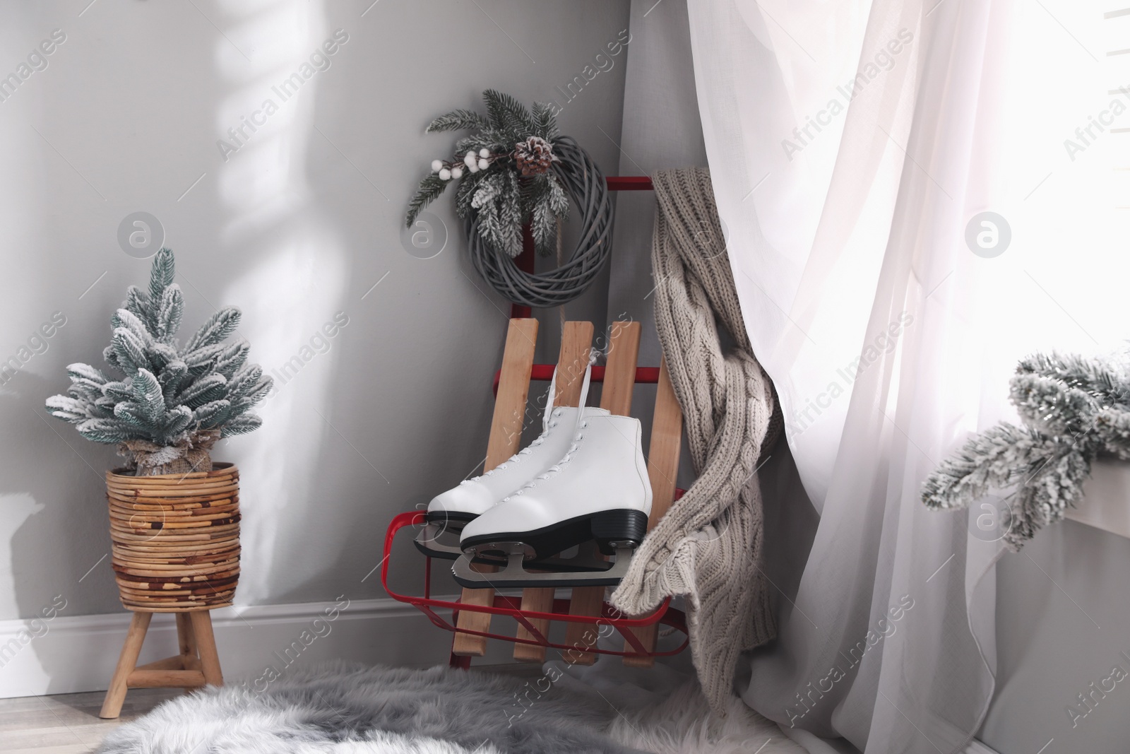 Photo of Pair of ice skates, sleigh and beautiful Christmas decor near window indoors