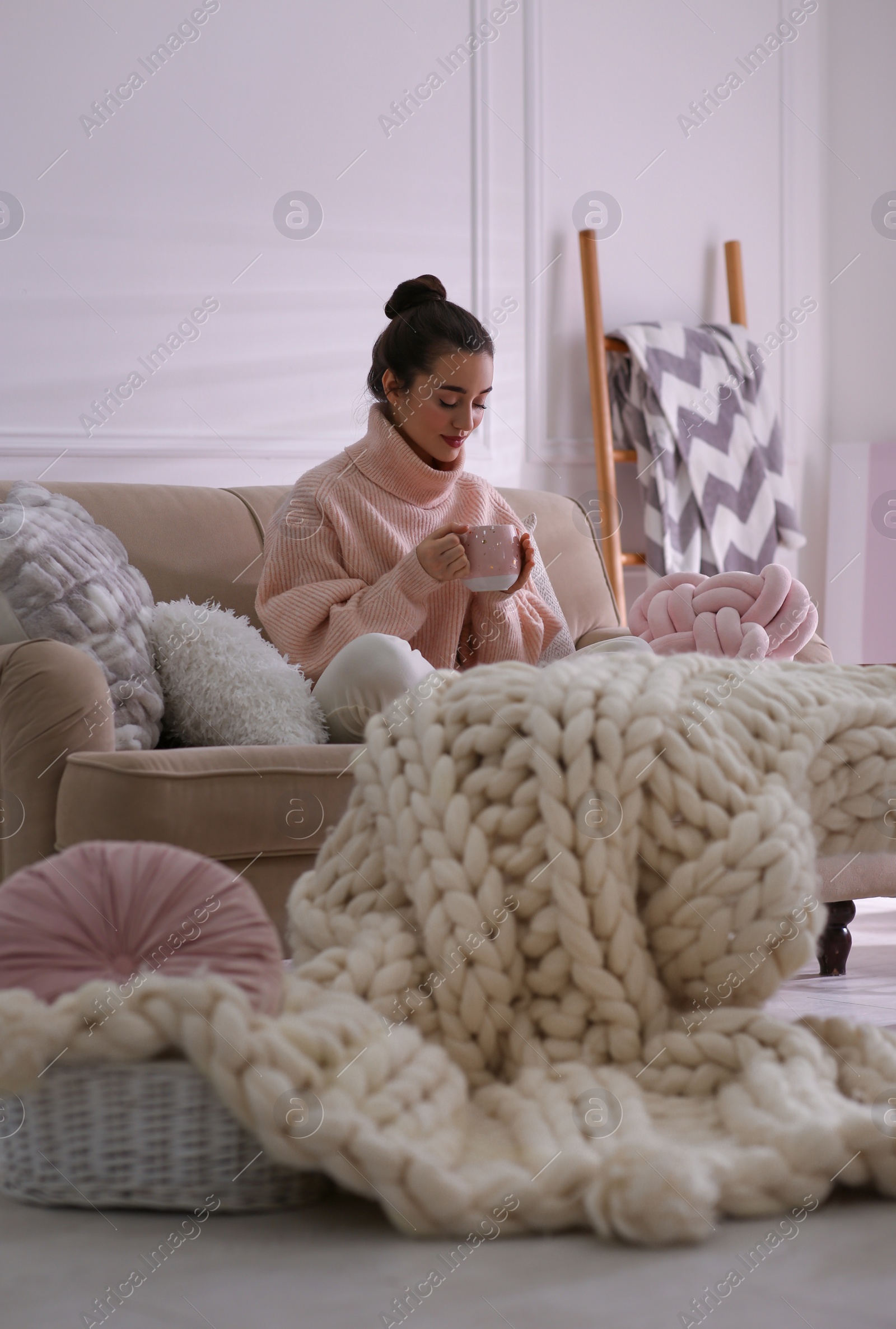 Photo of Beautiful young woman with cup of drink relaxing at home. Cozy atmosphere