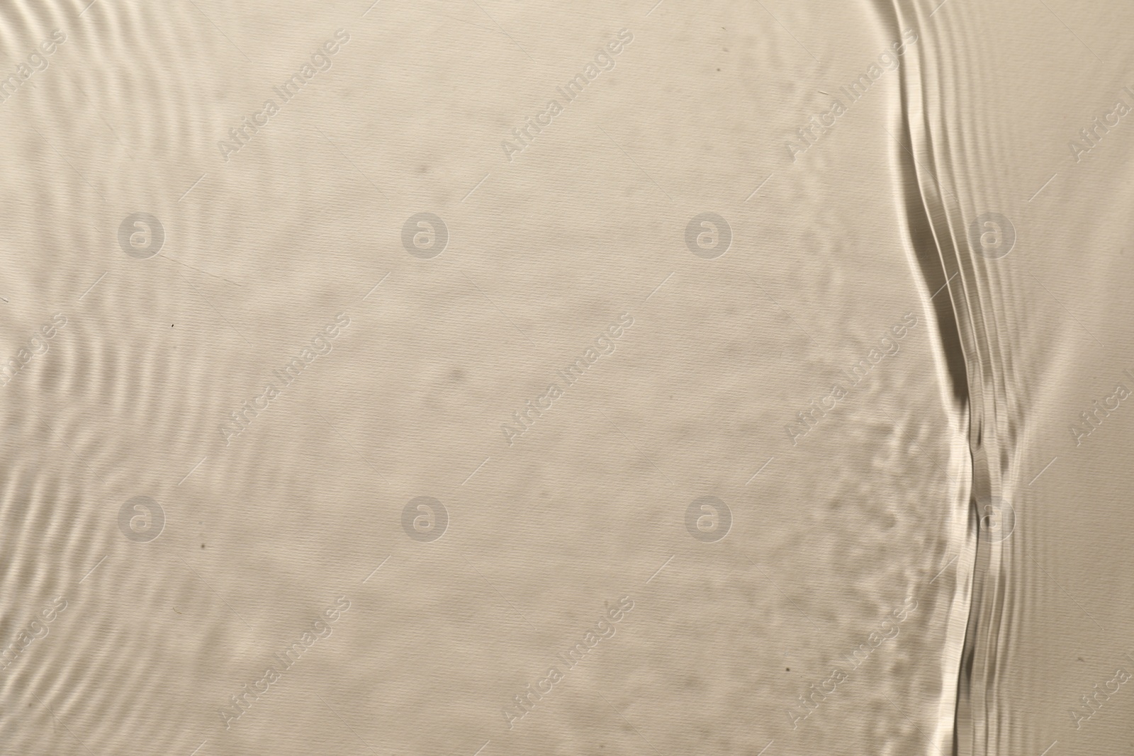 Photo of Rippled surface of clear water on beige background, top view